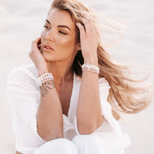 Load image into Gallery viewer, Blonde model on the beach wearing handmade crystal bracelets on both wrists
