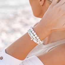 Load image into Gallery viewer, Model on the beach at sunset with three howlite 925 sterling silver and peruvian opal crystal bracelets on her wrist
